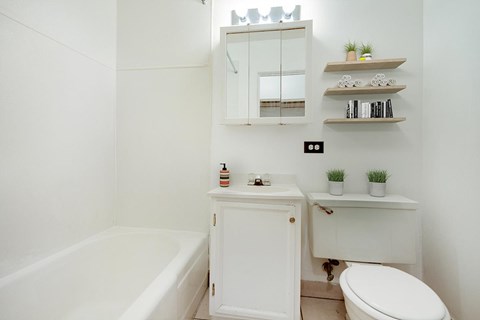 A white bathroom with a tub, toilet, and sink.