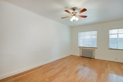 A room with a ceiling fan and wood flooring.