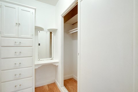 A white wardrobe with a mirror and drawers is in a room.