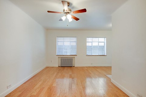 A room with a ceiling fan and wooden flooring.