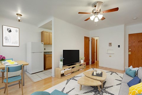 A living room with a television, a refrigerator, and a dining table.