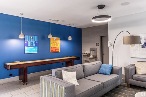 A living room with a grey couch and a blue wall.