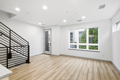 A room with a wooden floor and a staircase with a black railing.