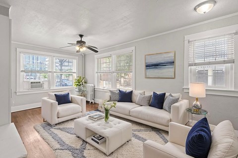 A living room with white furniture and a ceiling fan.