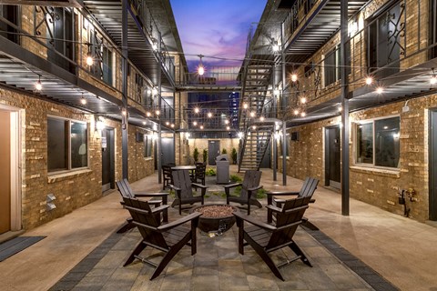 A patio with a table and chairs is surrounded by brick buildings.