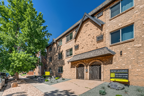 A brick apartment building with a sign that says "Now Leasing".