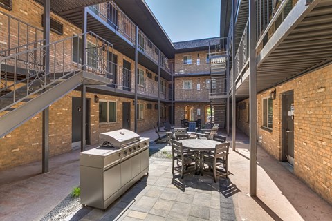 A courtyard with a table and chairs surrounded by brick buildings.