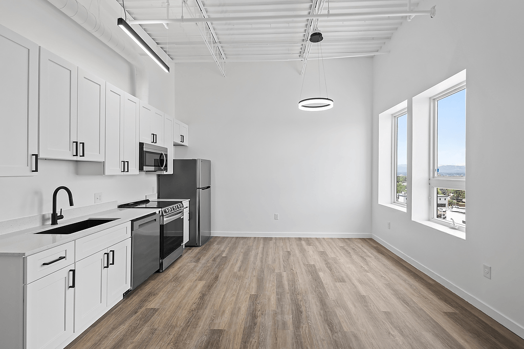 A kitchen with white cabinets and a wooden floor.