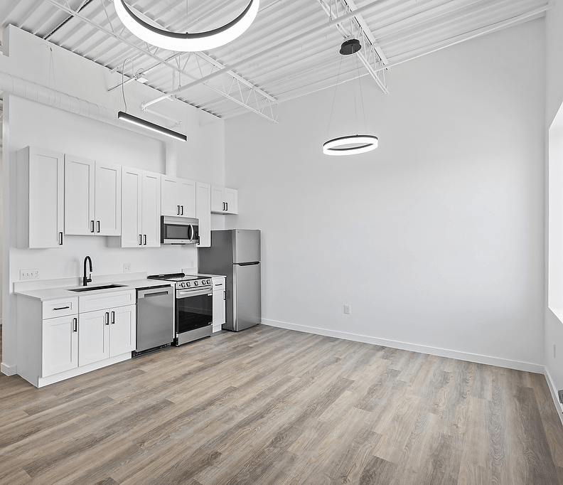 A kitchen with white cabinets and a wooden floor.