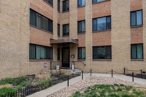 A brick building with a black fence and a small garden in front.