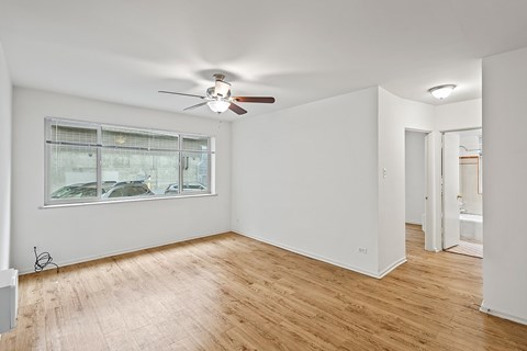 A room with a ceiling fan and a window with blinds.