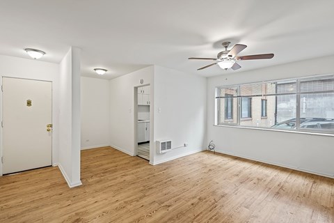 A room with a ceiling fan and a window overlooking a parking lot.