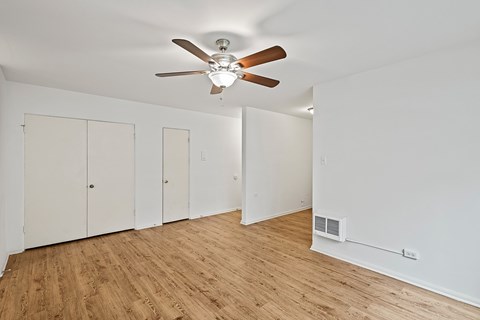 A room with a ceiling fan and wooden flooring.
