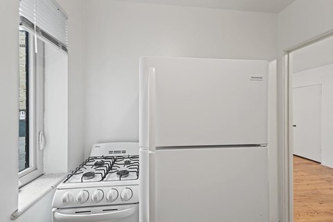 A white gas stove in a kitchen with a window to the left.