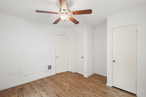 A room with a ceiling fan and three doors.
