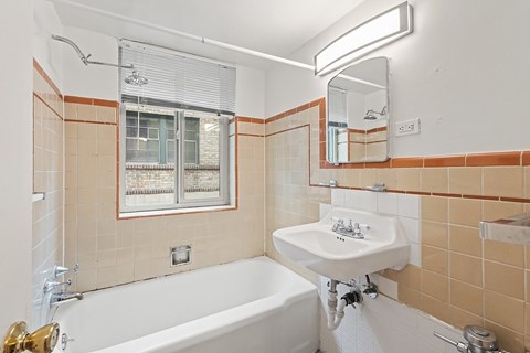 A bathroom with a white sink and a tub with a shower head.
