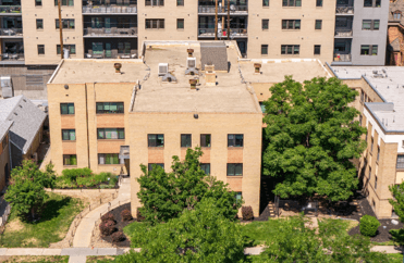 A large beige building with a tree in front of it.