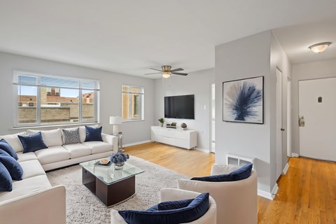 A living room with a white couch, blue pillows, and a glass coffee table.
