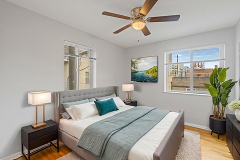 A bedroom with a bed, nightstand, and a ceiling fan.