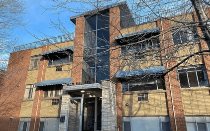 A large brick building with a black metal railing on the top floor.