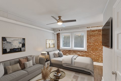A living room with a grey couch, a coffee table, and a brick wall.