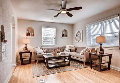 A living room with a couch, two end tables, and a ceiling fan.