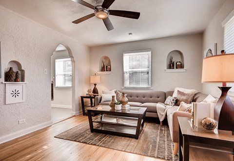 A living room with a grey couch, a coffee table, and a ceiling fan.