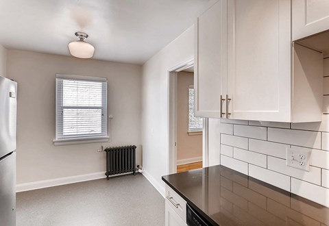 A kitchen with white cabinets and a black countertop.