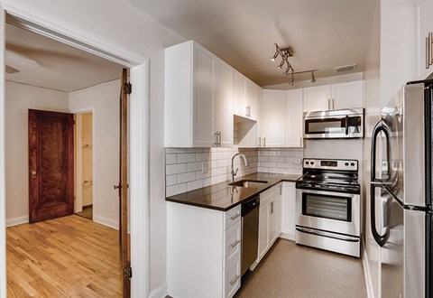 A kitchen with white cabinets and a black countertop.