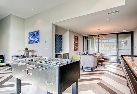 A foosball table is in the middle of a room with a couch and a chair.