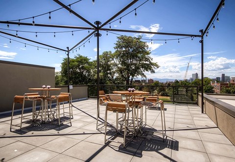 A patio with tables and chairs under a canopy of strings of lights.