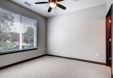 A room with a ceiling fan and a window with blinds.