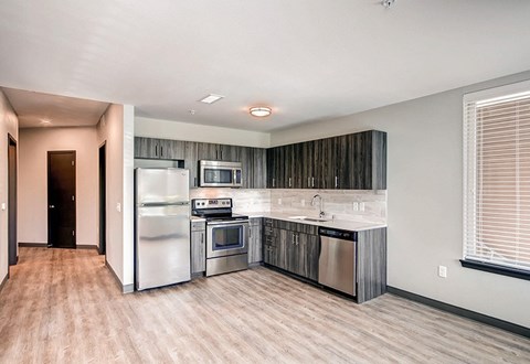 A modern kitchen with stainless steel appliances and wooden flooring.