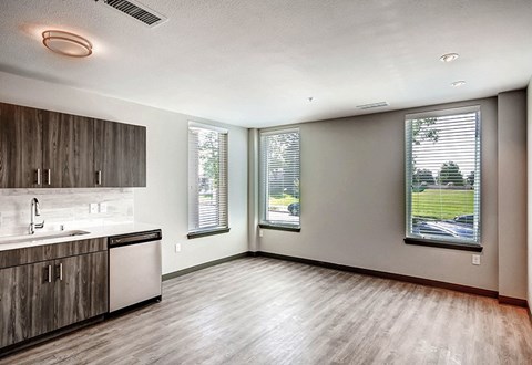 A kitchen with wooden cabinets and a window overlooking a street.