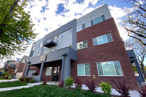 A modern building with a grey and red facade and a balcony on the second floor.