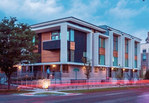 A modern building with a balcony and a tree in front of it.