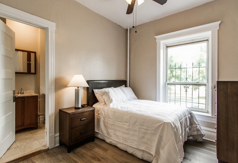 A bedroom with a bed, nightstand, and a window.