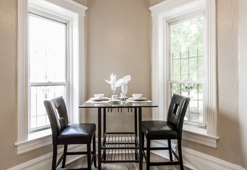 A dining table with two chairs and a white flower arrangement on top.