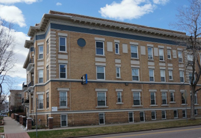 A large brick building with a blue stripe on the top floor.