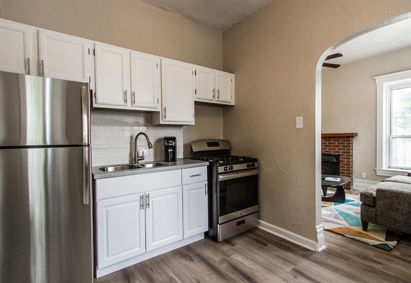 A kitchen with white cabinets and a stainless steel refrigerator.