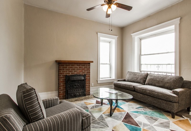 A living room with a fireplace, a striped chair, a coffee table, and a couch.