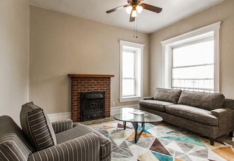 A living room with a fireplace, a striped chair, a coffee table, and a couch.