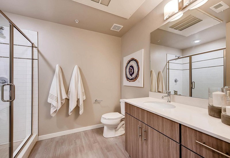 A bathroom with a toilet, sink, mirror, and towel rack.