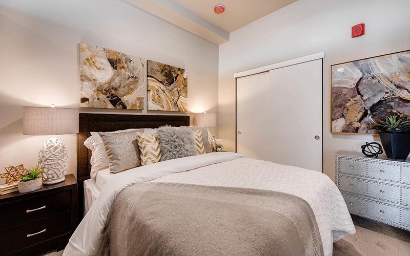 A bedroom with a large bed and a painting on the wall.