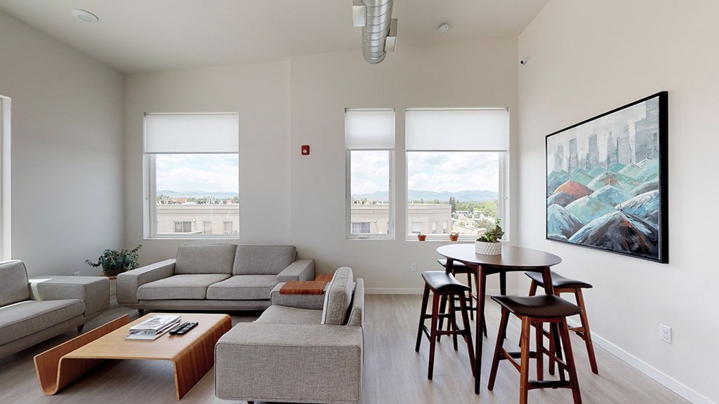 A living room with a grey couch, a coffee table, and a painting on the wall.