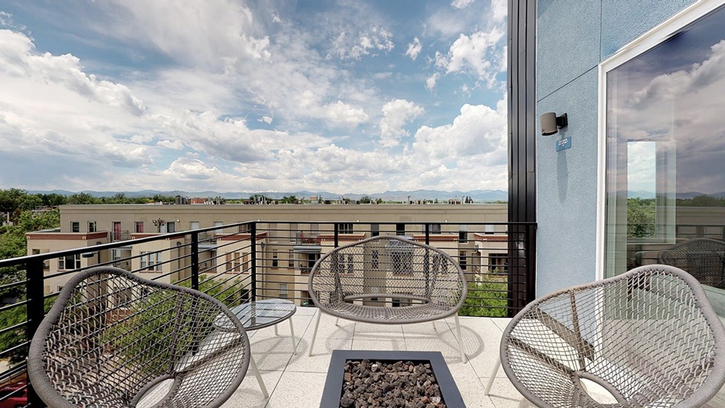 A balcony with a table and chairs overlooking a cityscape.