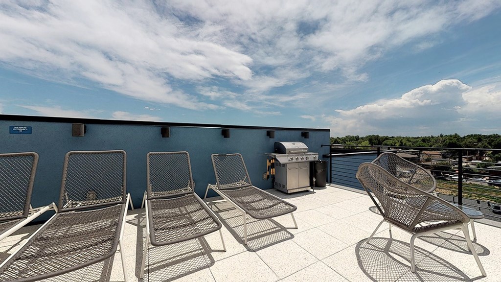 A patio with chairs and a grill on a sunny day.