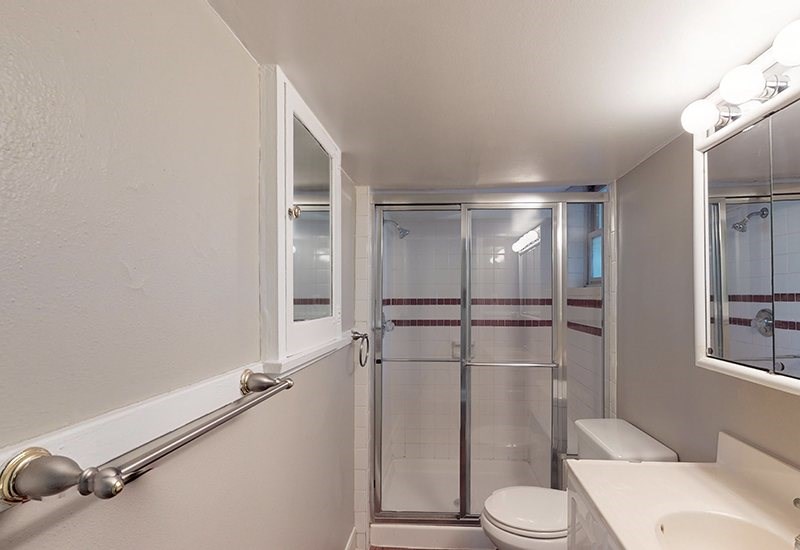 A white bathroom with a toilet, sink, and shower.