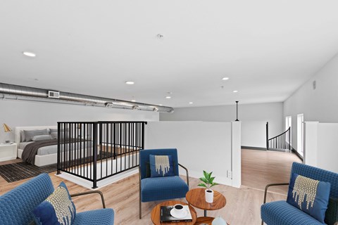 a living room with blue chairs and a bed in a room with a staircase