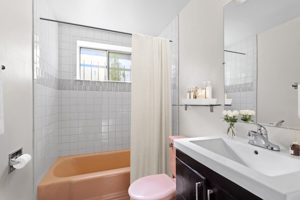 a bathroom with a peach bathtub and a white sink